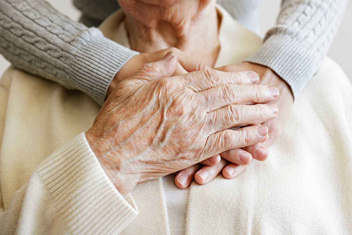 Mature female in elderly care facility gets help from hospital personnel nurse