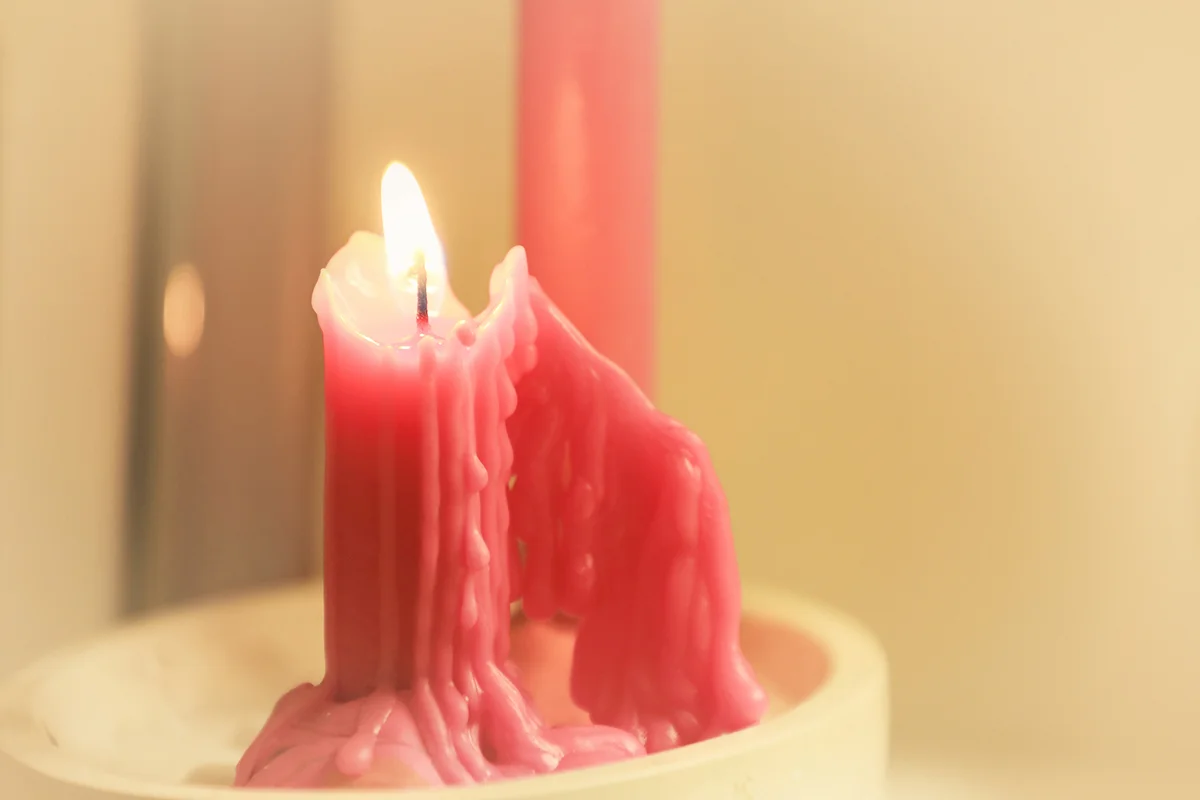 A red candle melting in a bowl