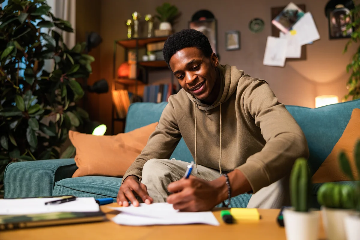 teenage student sitting in the living room writing