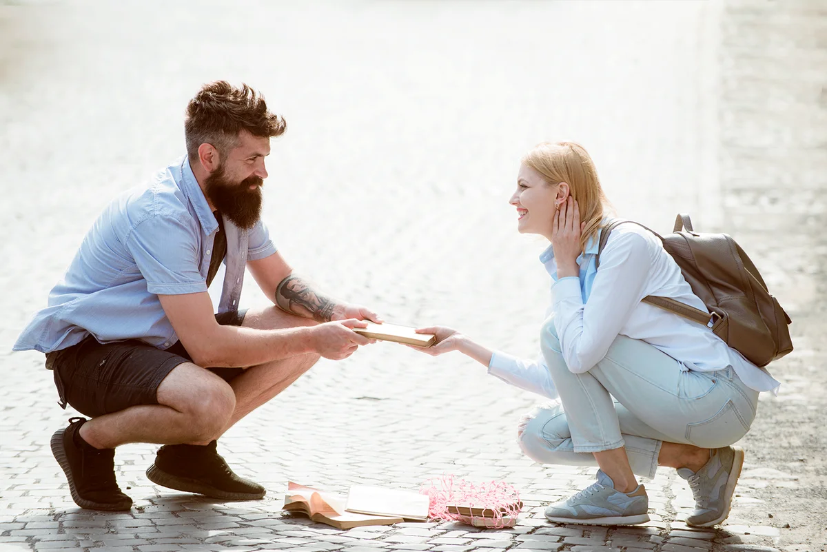 Couple in love on summer street. Hipster helping and looking at sexy girl. Bearded man and sexy woman falling in love. Love at first sight.