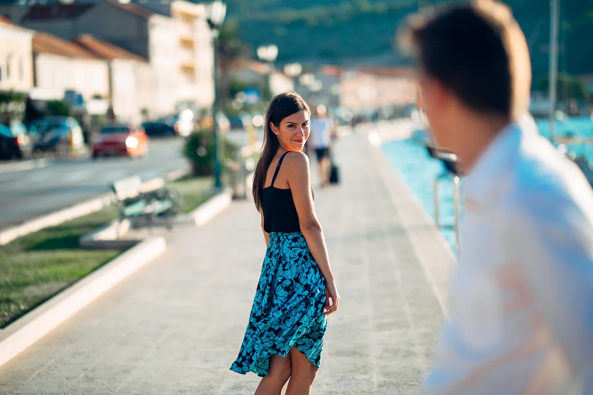 Young attractive woman flirting with a man on the street.Flirty smiling woman looking back on a handsome man.Female attraction.Love at first