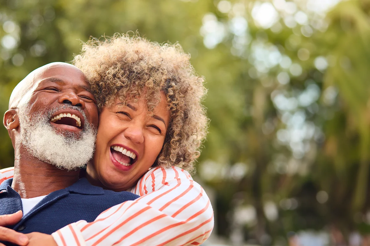 Portrait Of Loving Senior Couple Hugging Outdoors In Countryside Or Garden