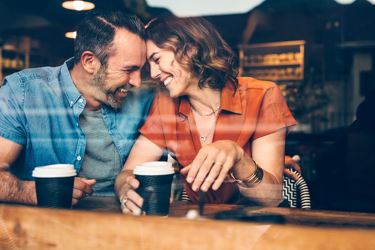 Beautiful couple in love having a coffee date. Loving couple sitting at cafe touching foreheads and smiling.