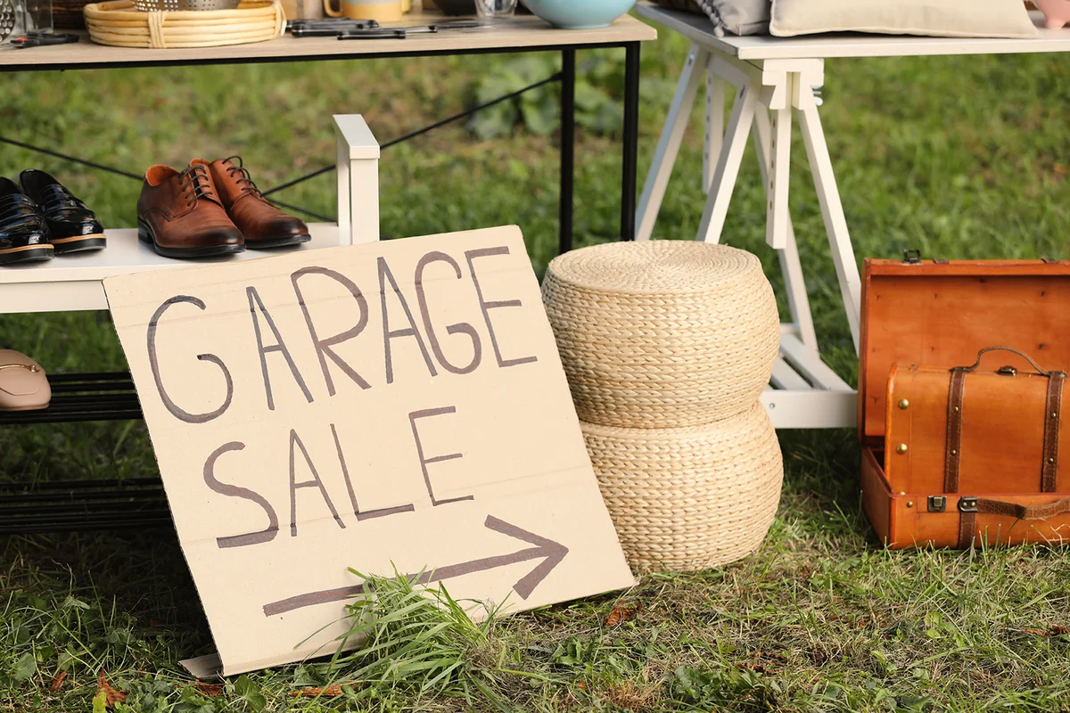 Sign Garage sale written on cardboard near tables