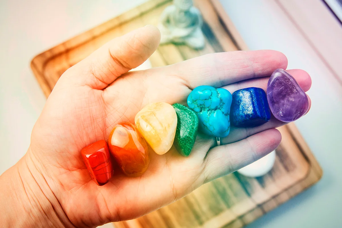 Woman hand sowing all seven color chakra crystal stones. Chakra energy flow healer concept