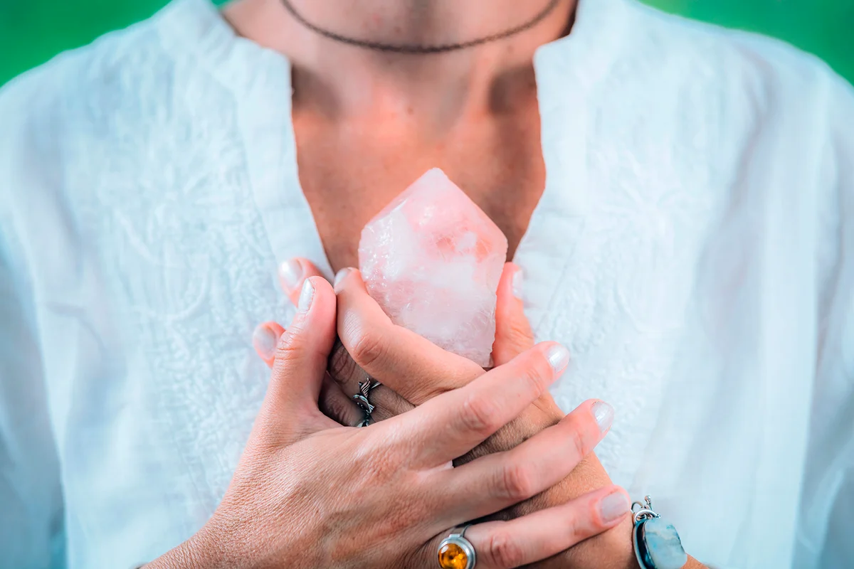 Self-worth meditation concept. Hands holding a rose quartz crystal, meditating, improving a sense of self-worth, focusing on being good and worthy of love and