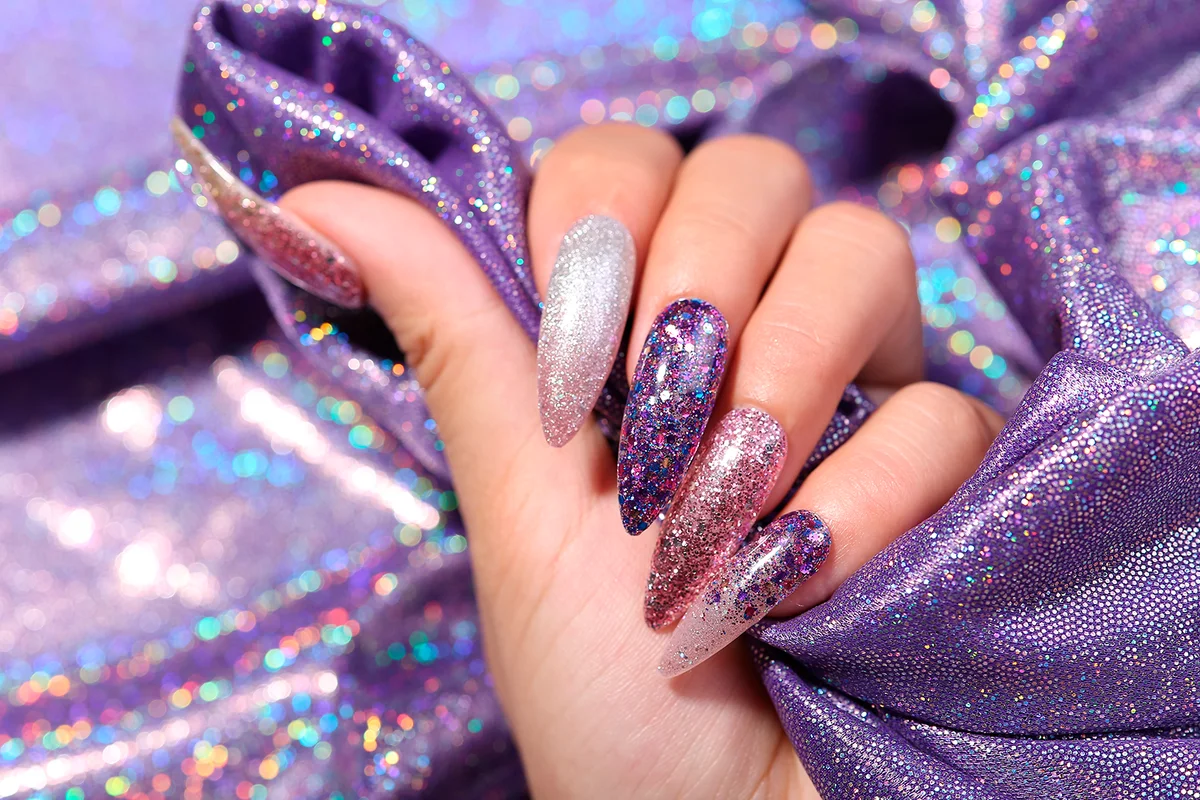 Female hand with silver nail design. Glitter silver nail polish manicure. Model hand with perfect manicure hold white lace fabric on white background.