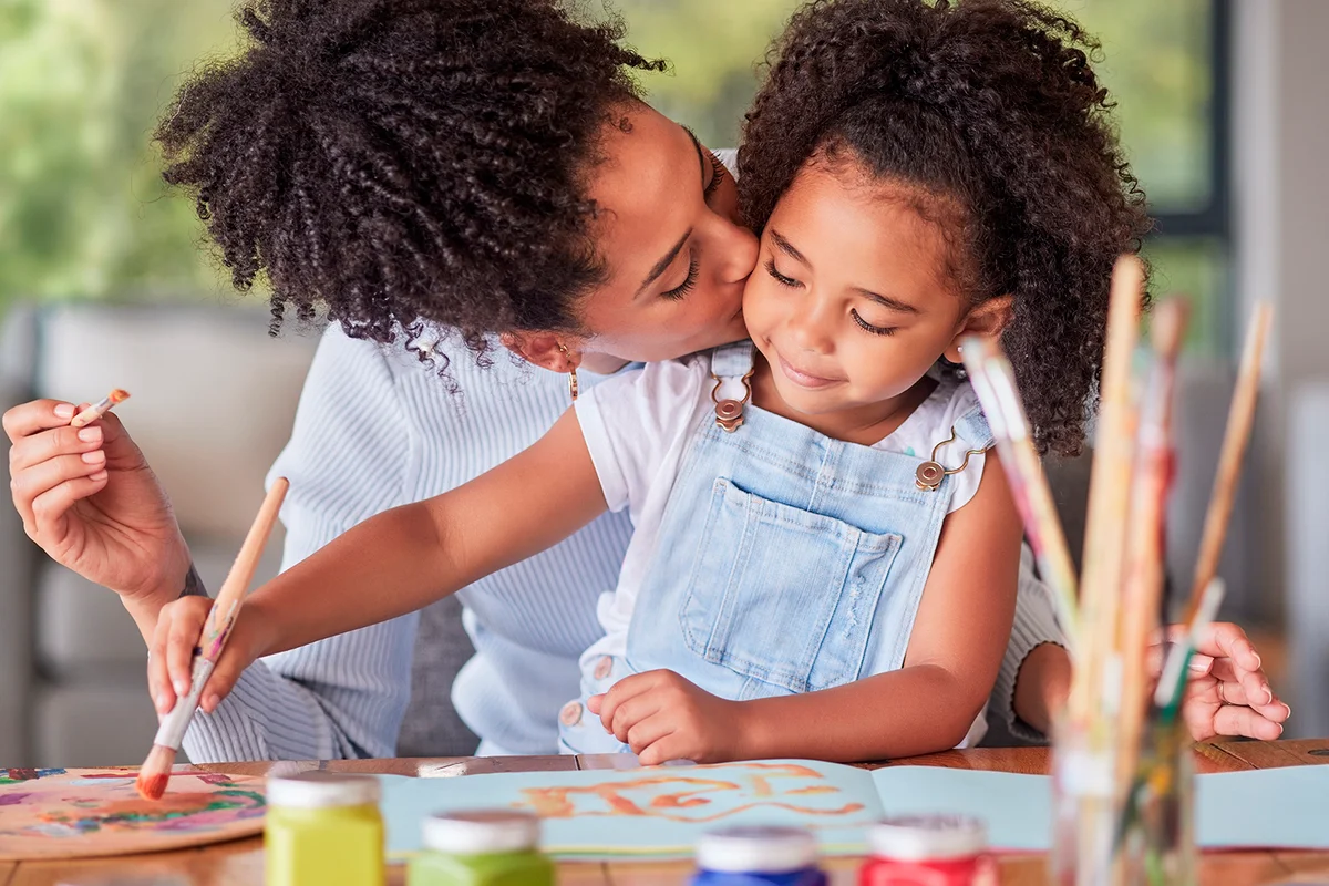 Creative, art and mother painting with her child with colorful paint, paint brush and paper. Creativity, love and care between a happy mom and girl doing a hobby or education project together at home