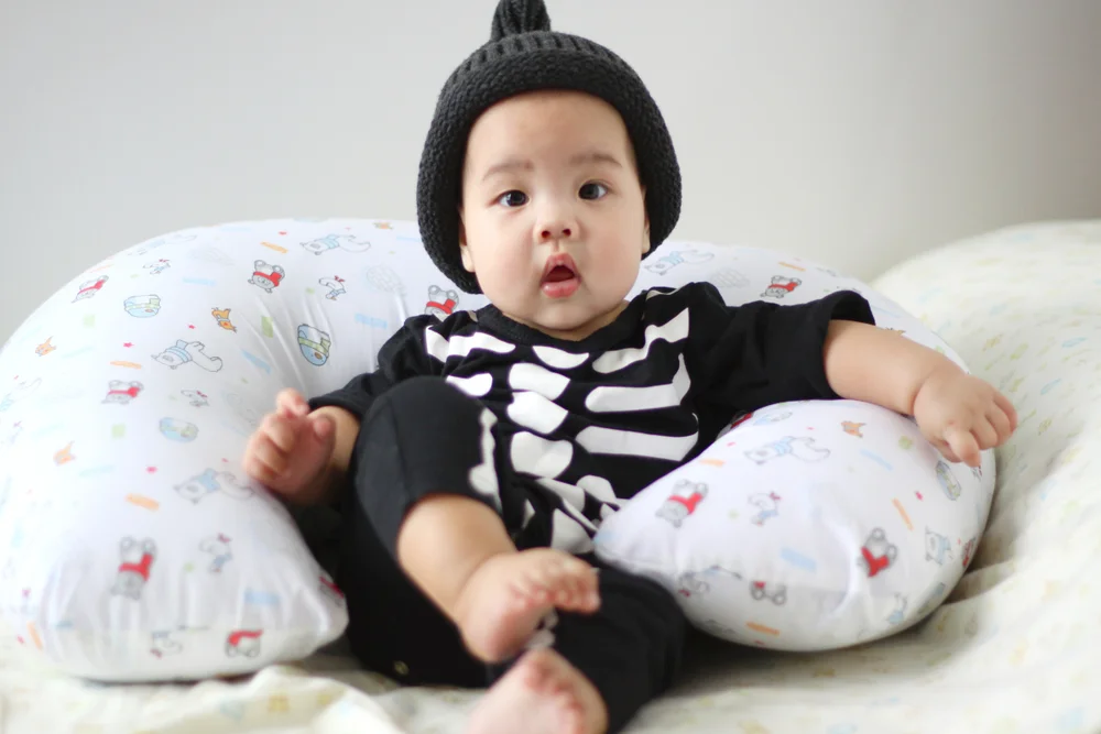 Cute asian baby wearing a skeleton onesie and a black beanie