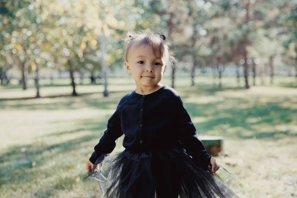 Happy little girl in nature wearing black clothes and a tutu