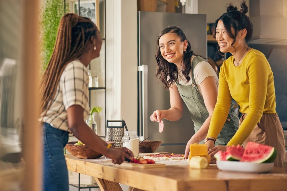 Diverse group of girlfriends smile and cook pizza in kitchen, bonding and having fun.