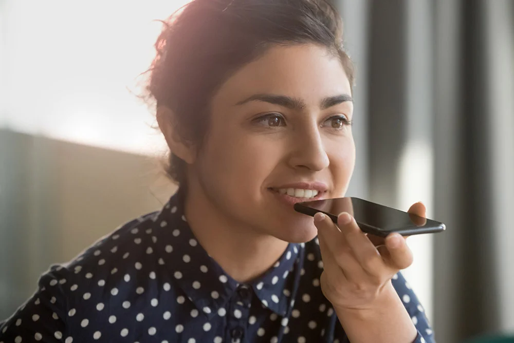 Young attractive Indian woman talks on the phone through the speaker at home