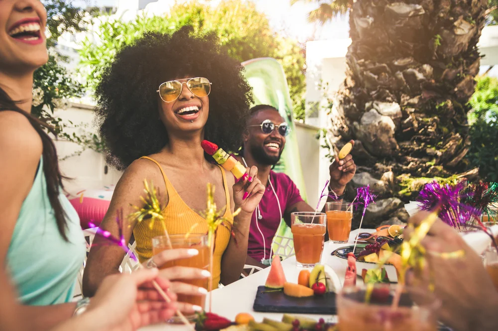 Multiracial group of friends having fun and drinking cocktails at a backyard home party