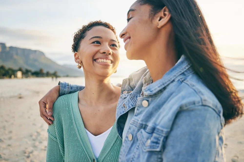Happy black lesbian couple looking romantically at each other on a beautiful beach.