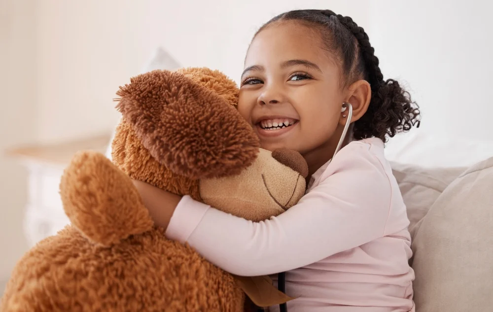 Black little girl hugging her teddy bear