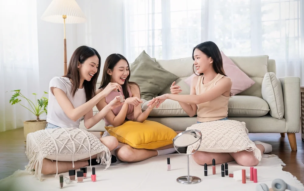 Group of young happy asian girls paint their nails in the livingroom