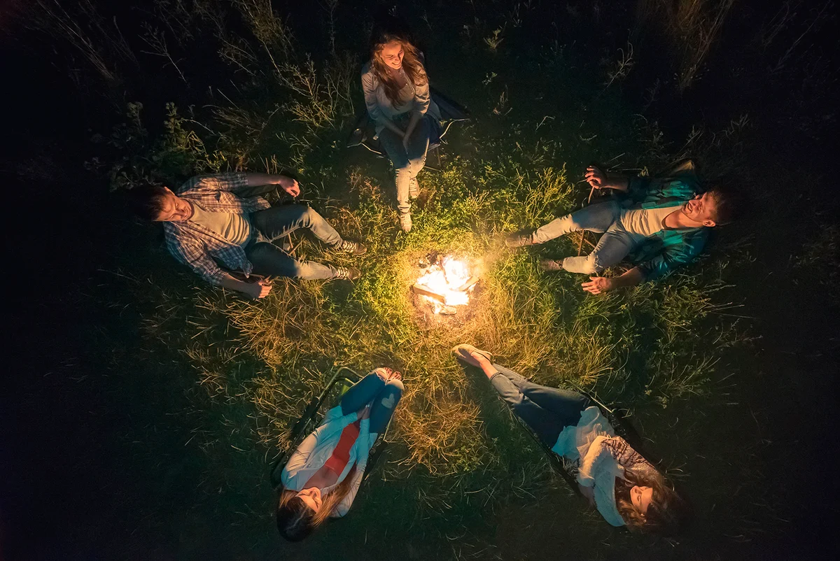 The five people sit near the bonfire. view from above, evening night time