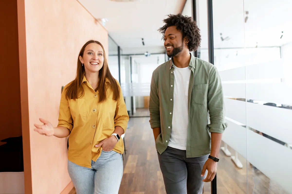 Two people walking down a hallway talking