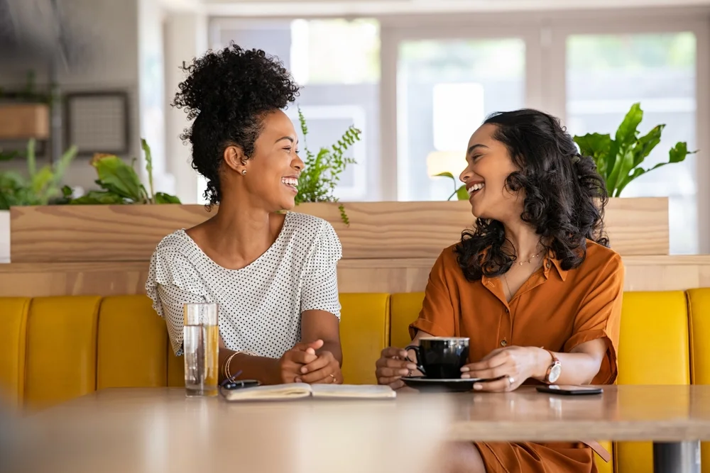 Two friends having coffee and laughing