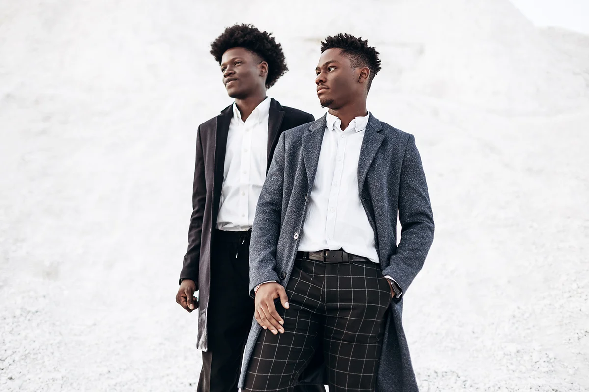 Two trendy African black men, against the backdrop of rocky mountains, in stylish classic clothes, with fashionable hairstyle