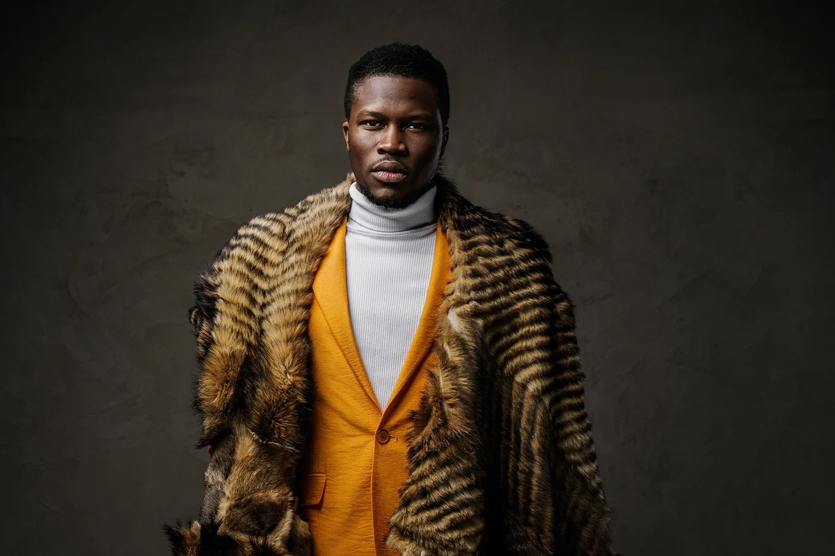 Portrait of a stylish dark-skinned man wearing a yellow jacket and a wild animal skin draped over his shoulders