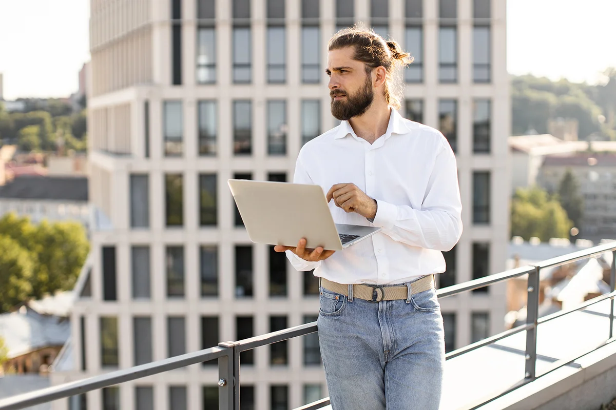 Young businessman working on rooftop with laptop in hand.