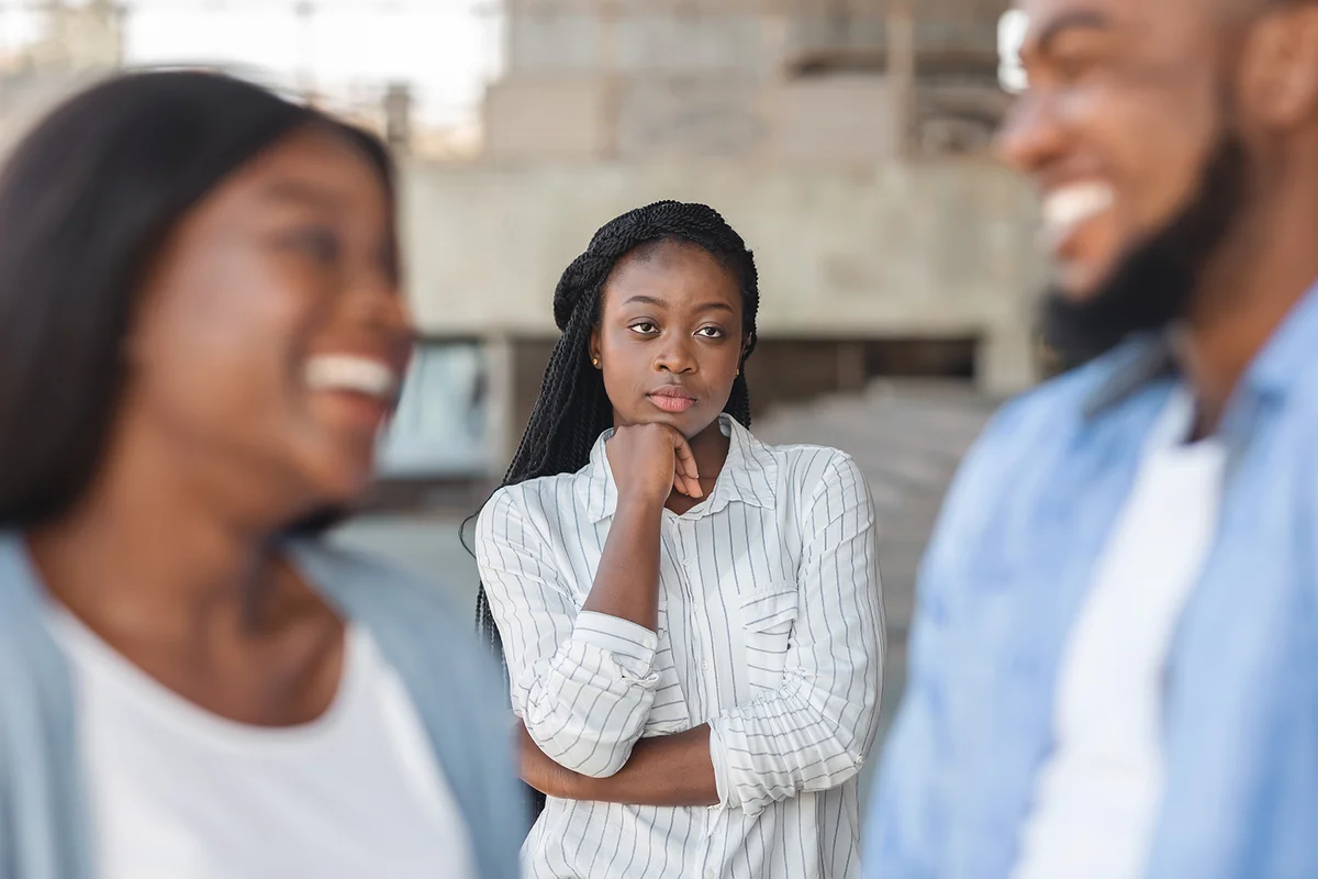 Upset black woman watching her ex boyfriend happy in relations with new girlfriend, looking jealous on background