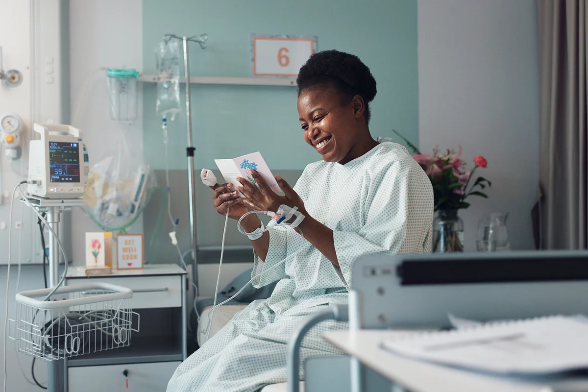 Woman, reading card and bed in hospital for message, get well soon or motivation with smile, hope and recovery.