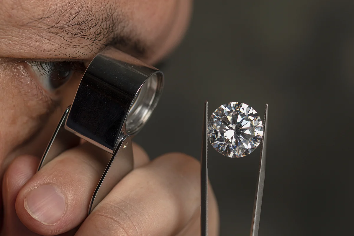 Close up male jeweller. Jeweller looking diamond though loupe.