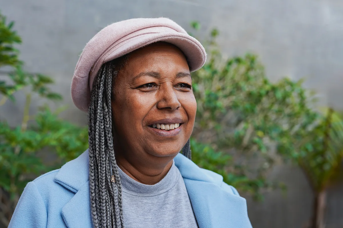 Happy african senior woman smiling in front of camera during winter travel vacation in the city