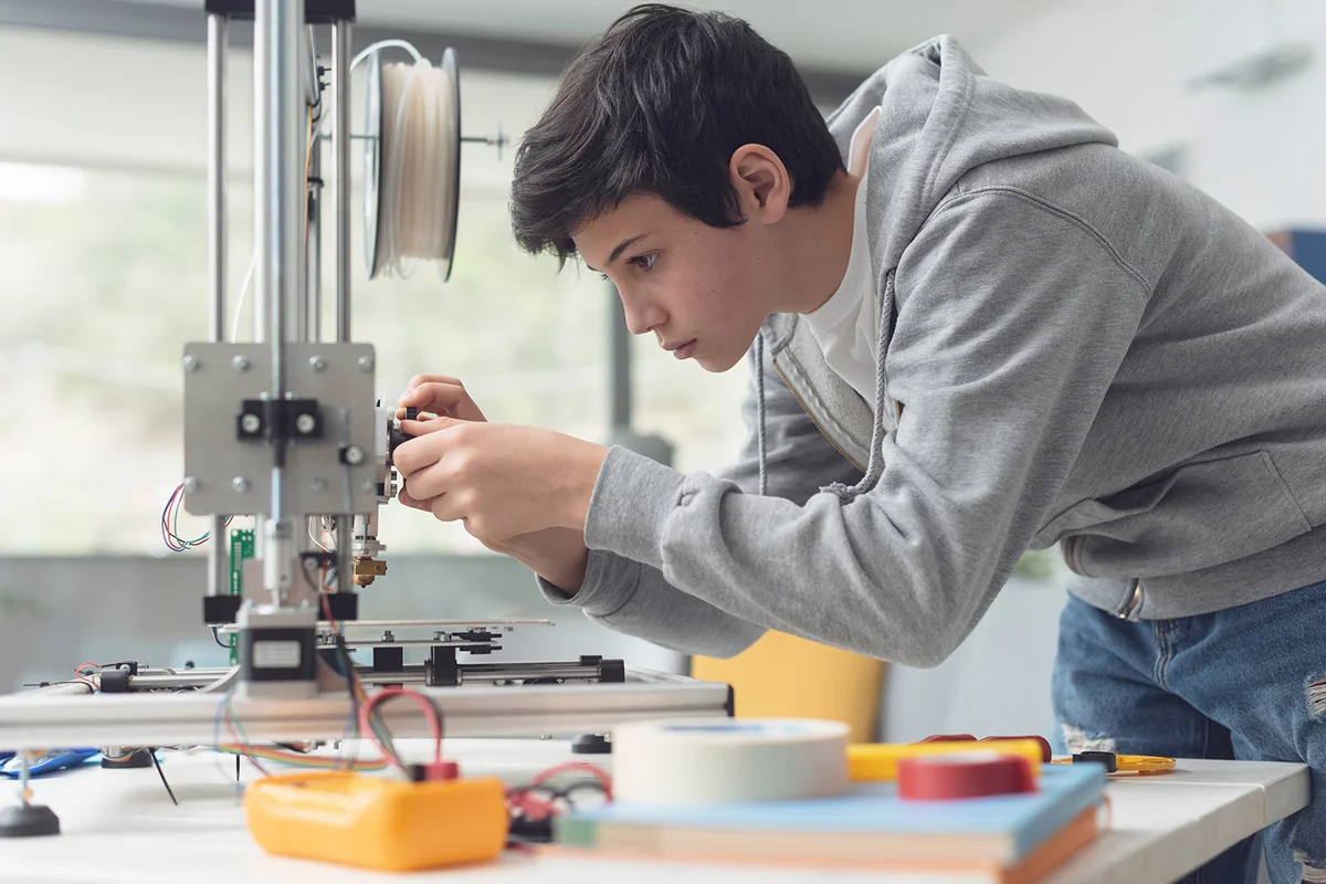 Smart young student learning 3D printing, he is checking the printer