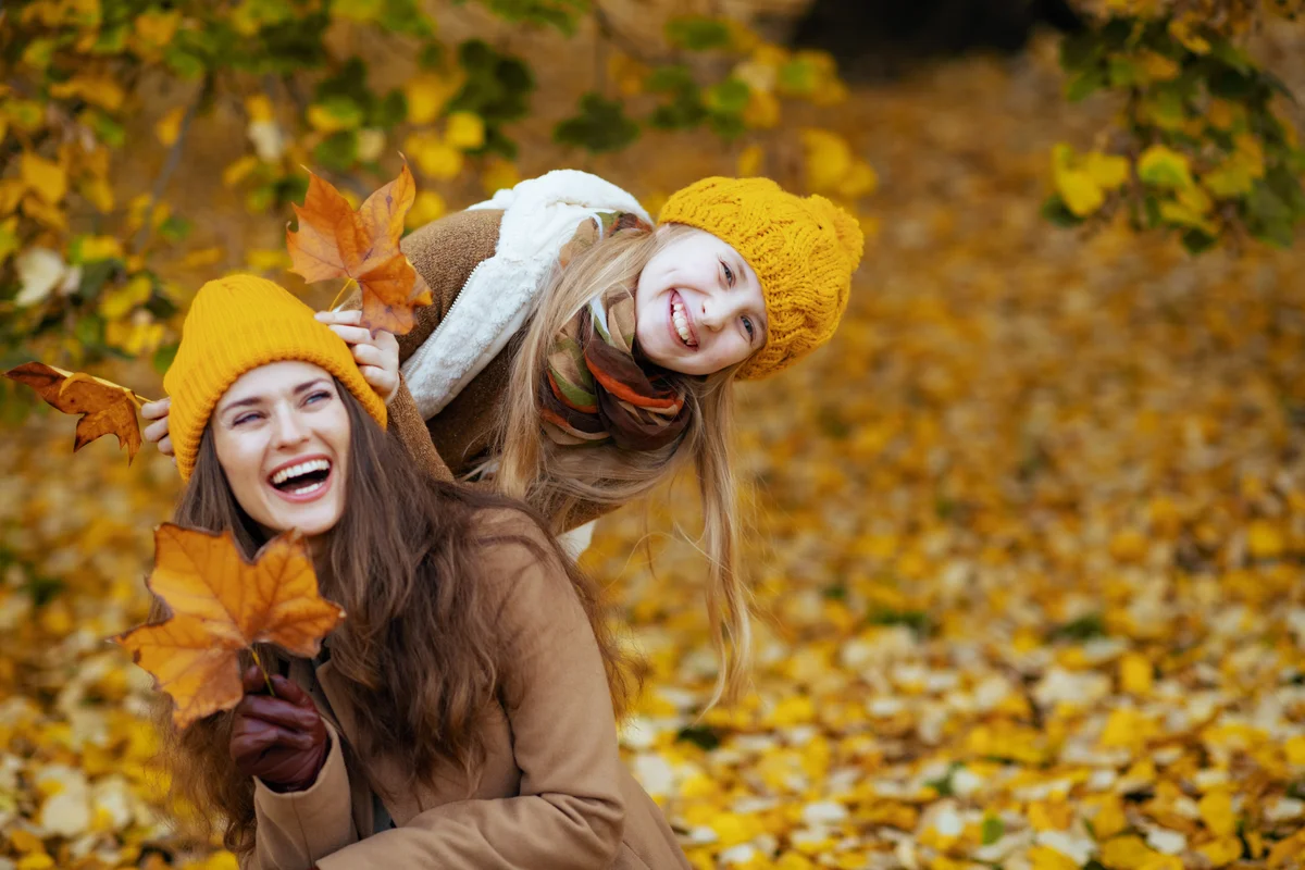 mother and daughter playing in fall leaves