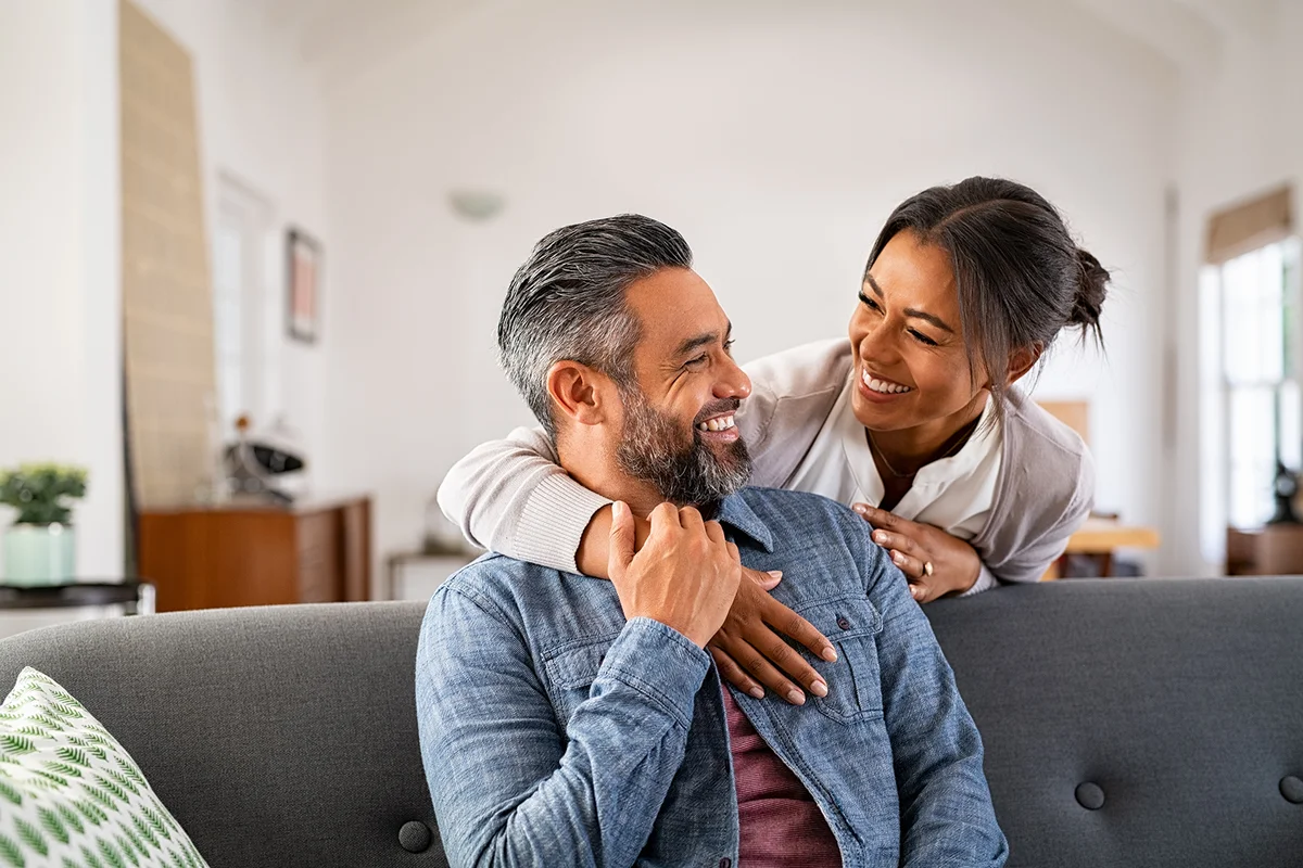 woman hugging her husband on the couch from behind in the living room