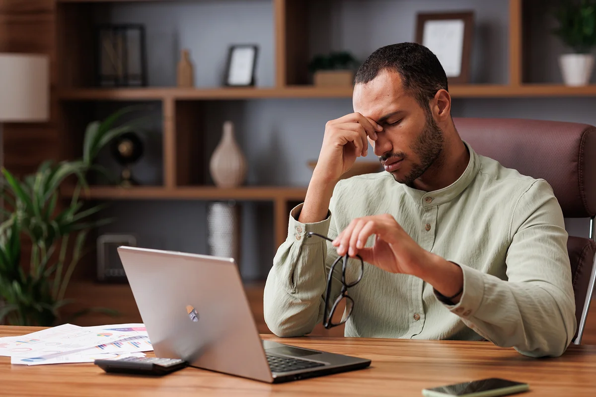 businessman after exhausting paperwork taking off eyeglasses and feeling eye strain