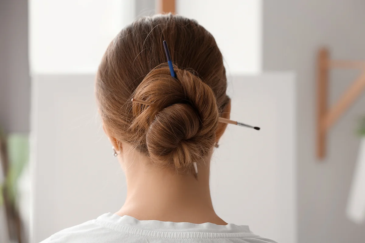 Female artist with brushes in her hair, back view