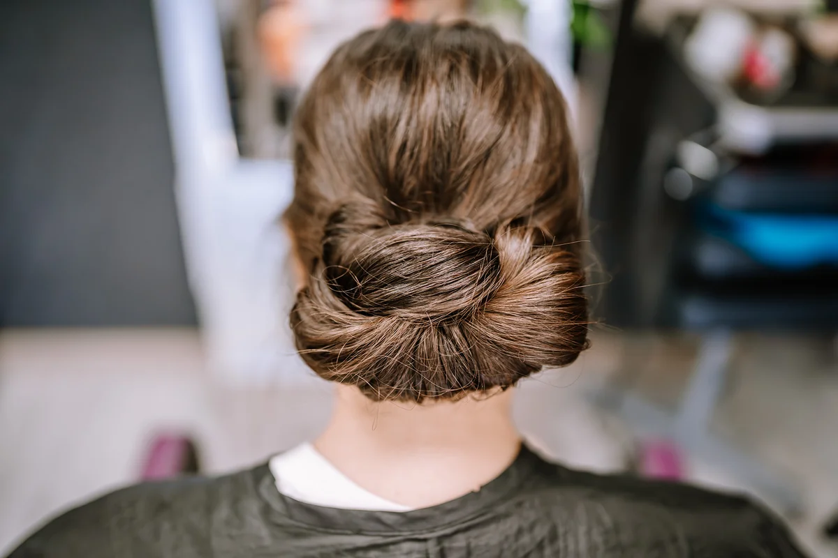 Elegant updo hairstyle on a woman in a salon, viewed from behind.