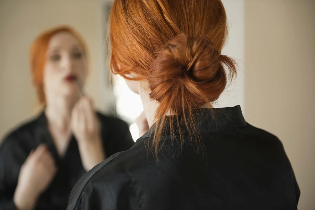 Back view of young woman applying makeup