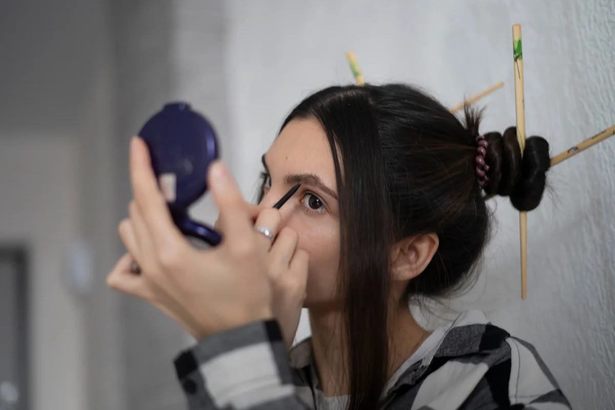 Young Woman Precision Painting Eyebrows With Brown Pencil in the morning