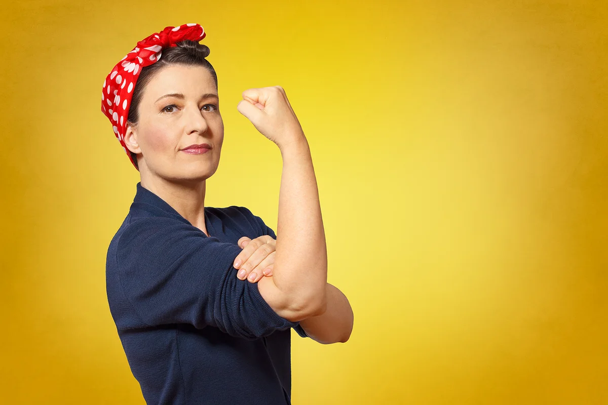 woman with a clenched fist rolling up her sleeve, text space, tribute to american icon Rosie Riveter