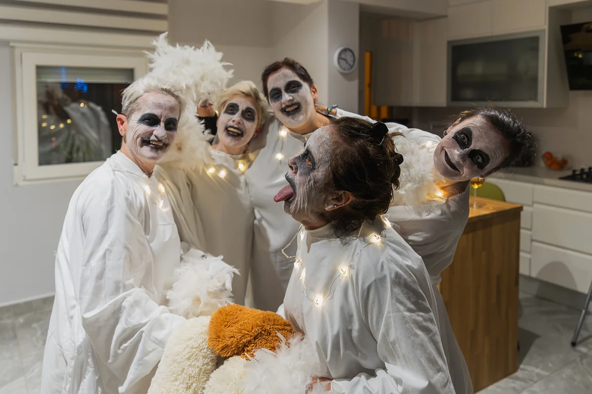 friends wearing ghost costumes with playful makeup enjoy a spirited party