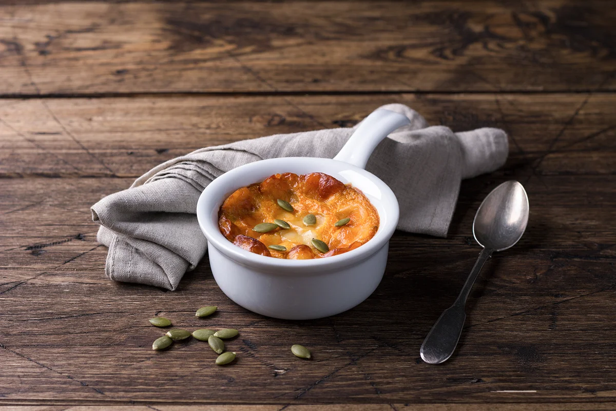 Pumpkin cheese casserole in ceramic mold with pumpkin seeds