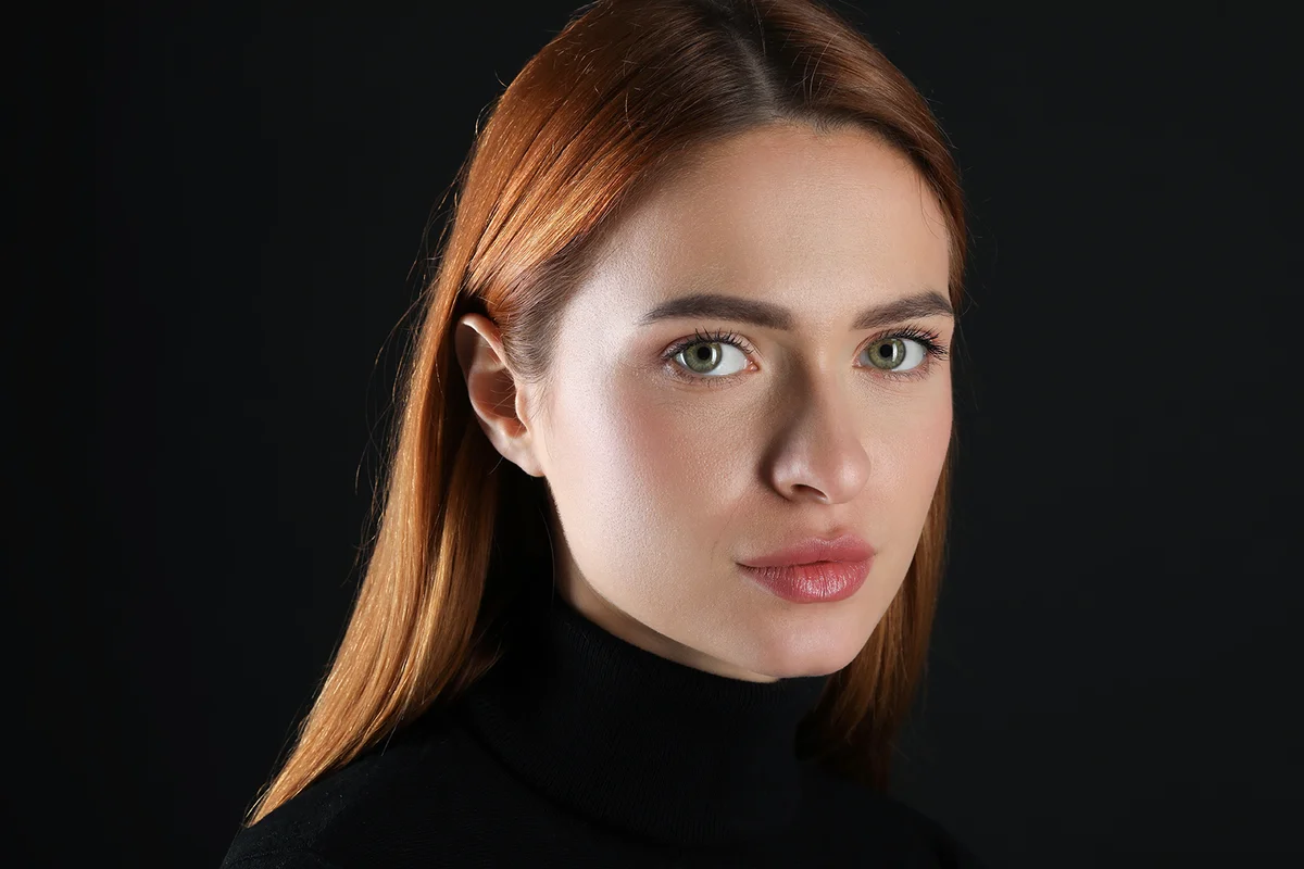 Young woman with scary eyes on black background
