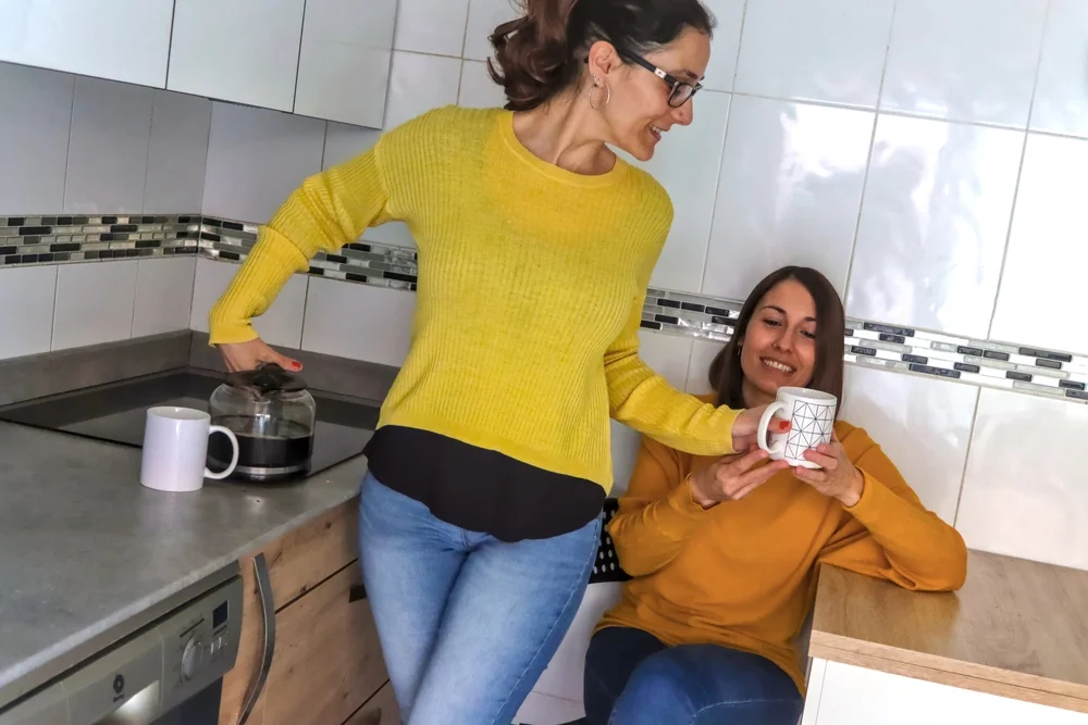 woman giving another woman a cup of coffee