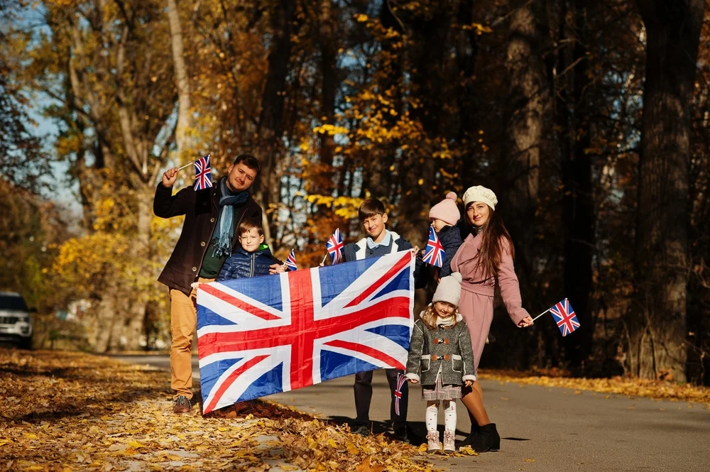 A family with four kids holding British flags in a park in Autumn