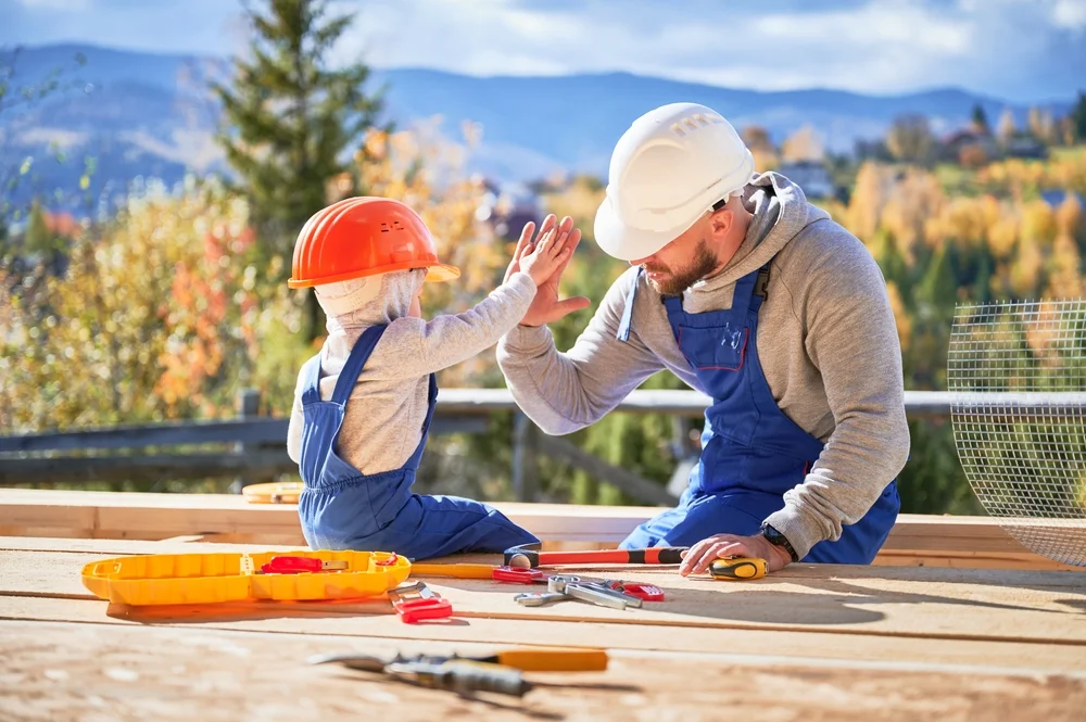 Father and his toddler building something together on a sunny day.