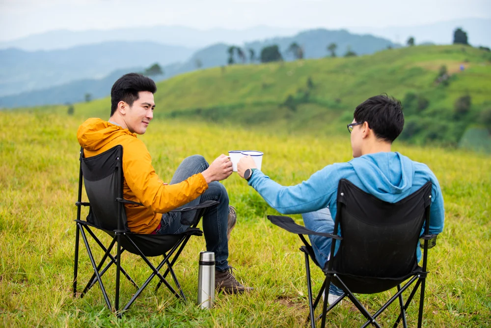 Asian male friends enjoy a coffee outdoors after a hike