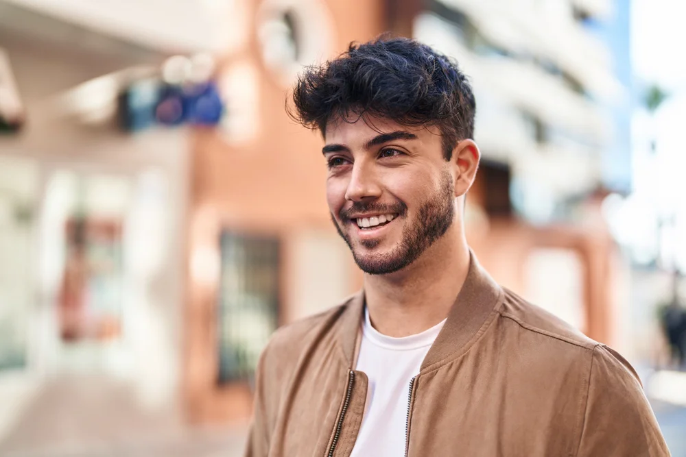 A young Hispanic man smiling in the street