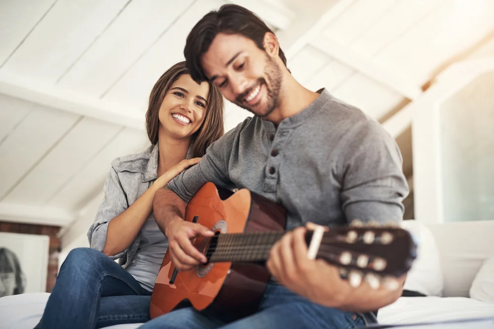 A man romantically plays the guitar with a woman next to him