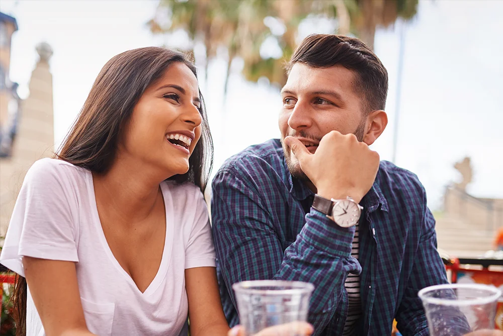 A man pays attention to a woman at an outdoor restaurant