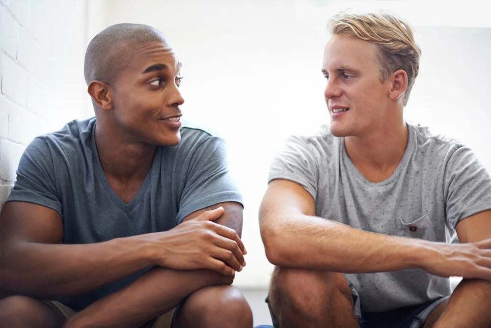 Two male friends talking to each other closely